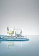 City cocktailglas stående ved af et city vandglas på en bakke ovenpå et hvidt bord.
